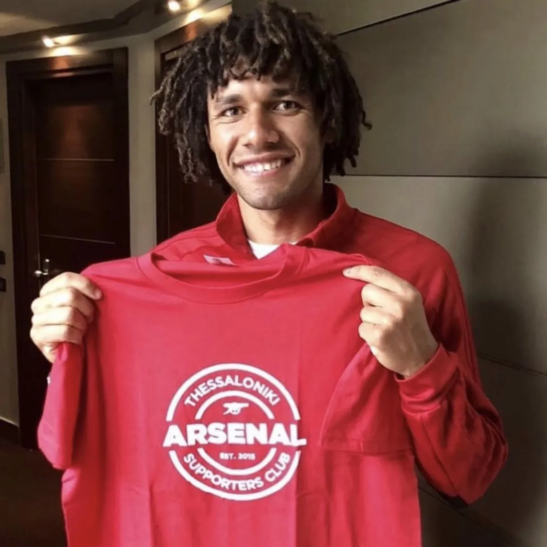 Mohamed Elneny holding shirt with logo